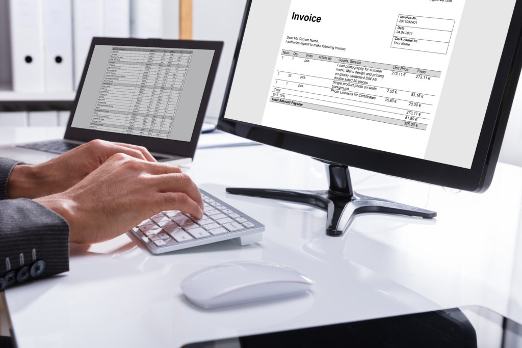 Businessperson Checking Invoice On Computer accounting and bookkeeping services for nonprofits